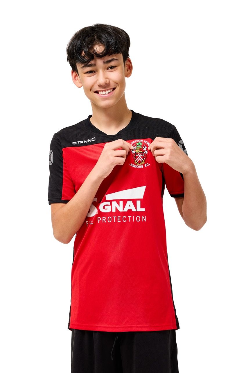 A young boy wearing a football kit, posing with a football against a clean white studio background.