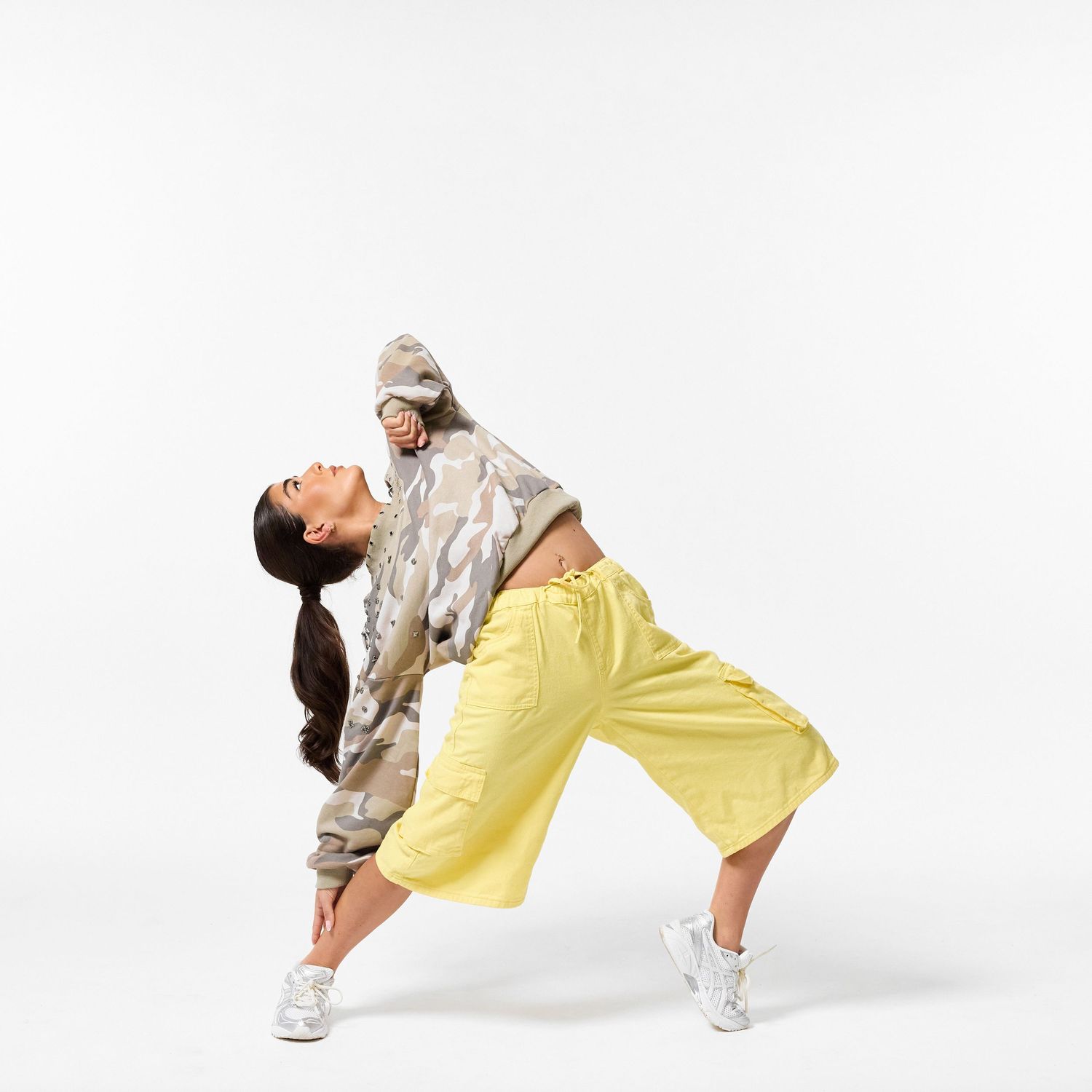 A modern dancer wearing stylish streetwear, captured in a dynamic, expressive pose against a clean white background.