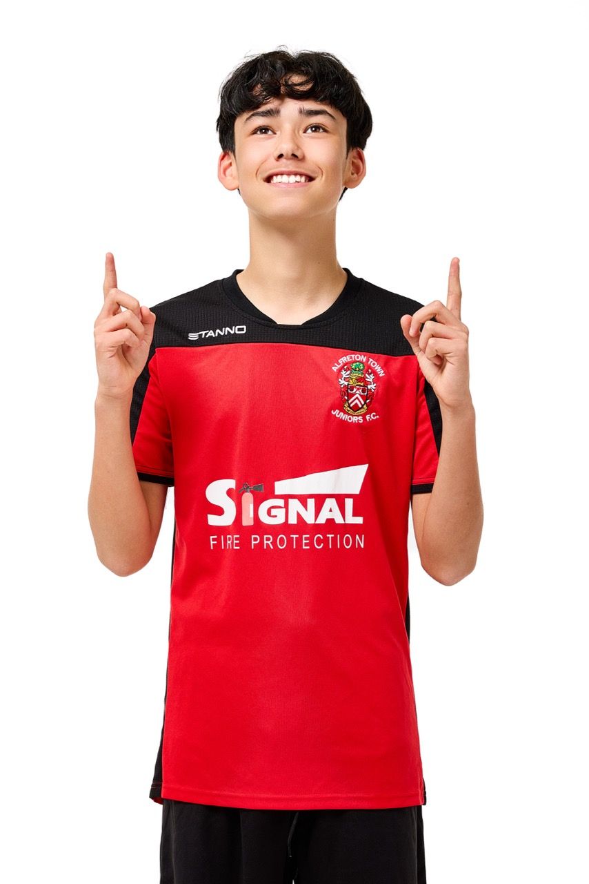 A young boy wearing a football kit, posing with a football against a clean white studio background.