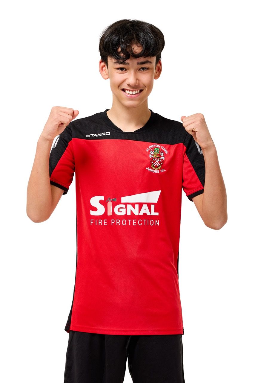 A young boy wearing a football kit, posing with a football against a clean white studio background.