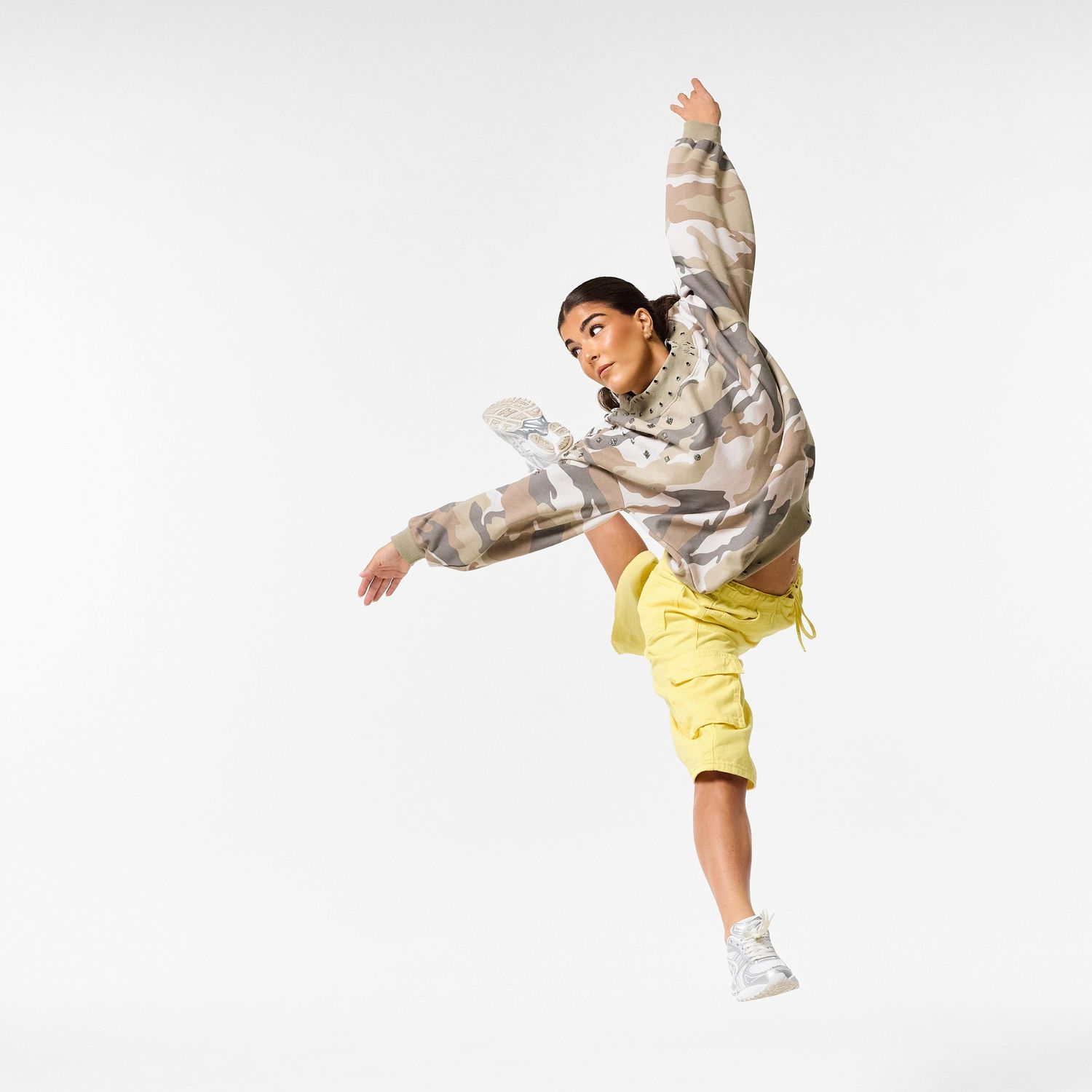 A modern dancer wearing stylish streetwear, captured in a dynamic, expressive pose against a clean white background.