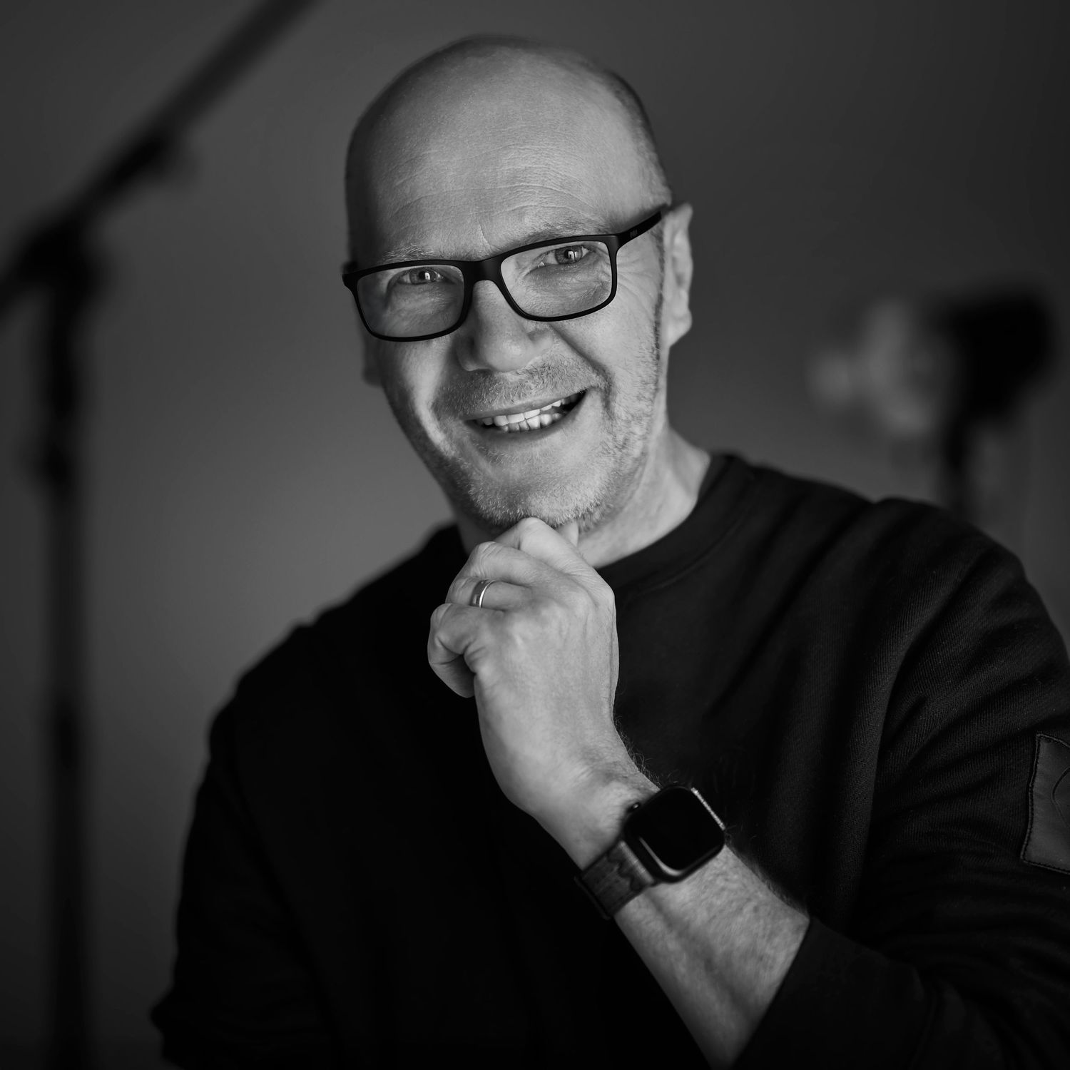 A professional headshot of the photographer smiling at the camera, set against a clean and minimalist studio background.