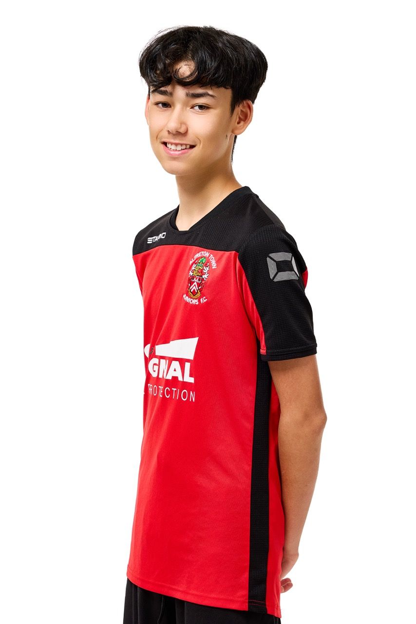 A young boy wearing a football kit, posing with a football against a clean white studio background.