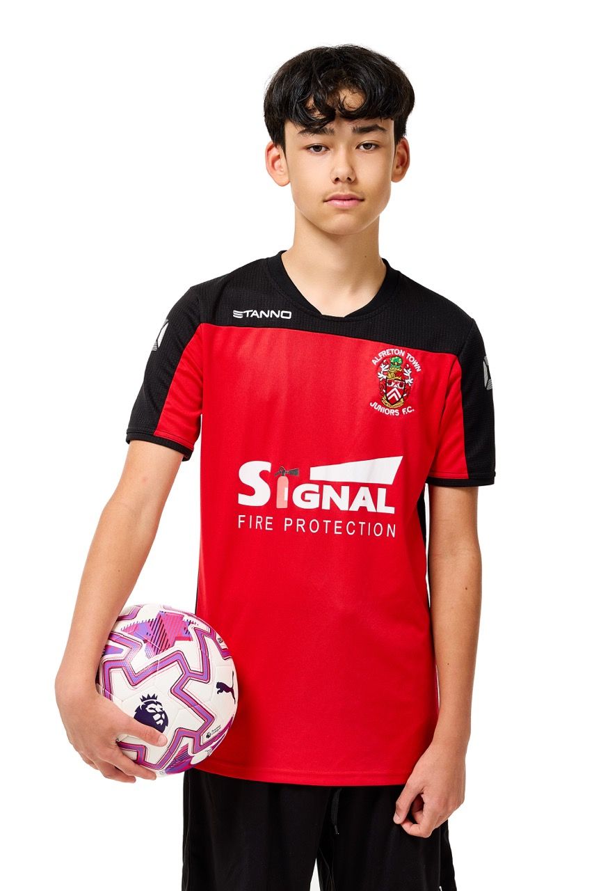 A young boy wearing a football kit and holding a ball, posing with a football against a clean white studio background.