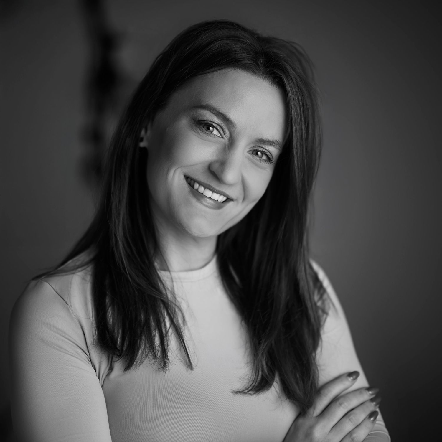 A professional headshot of the photographer smiling at the camera, set against a clean and minimalist studio background.
