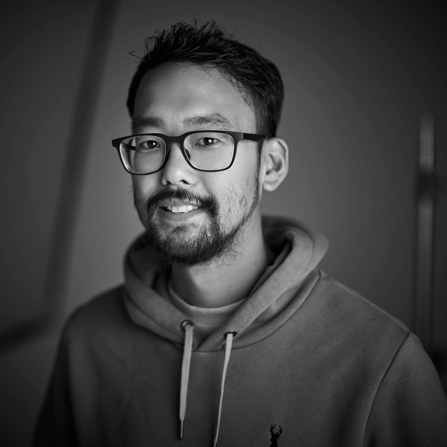 A professional headshot of the photographer smiling at the camera, set against a clean and minimalist studio background.