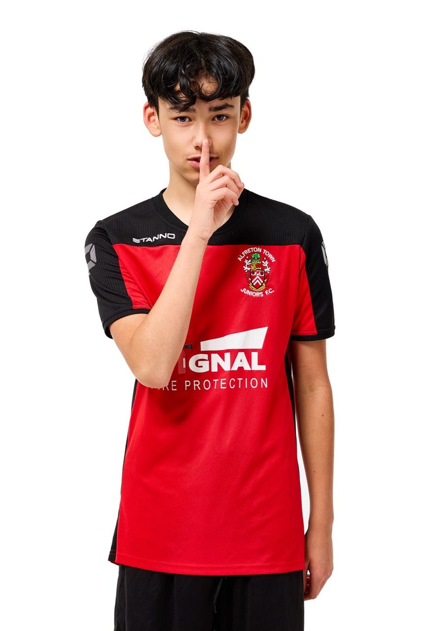 A young boy wearing a football kit, posing with a football against a clean white studio background.