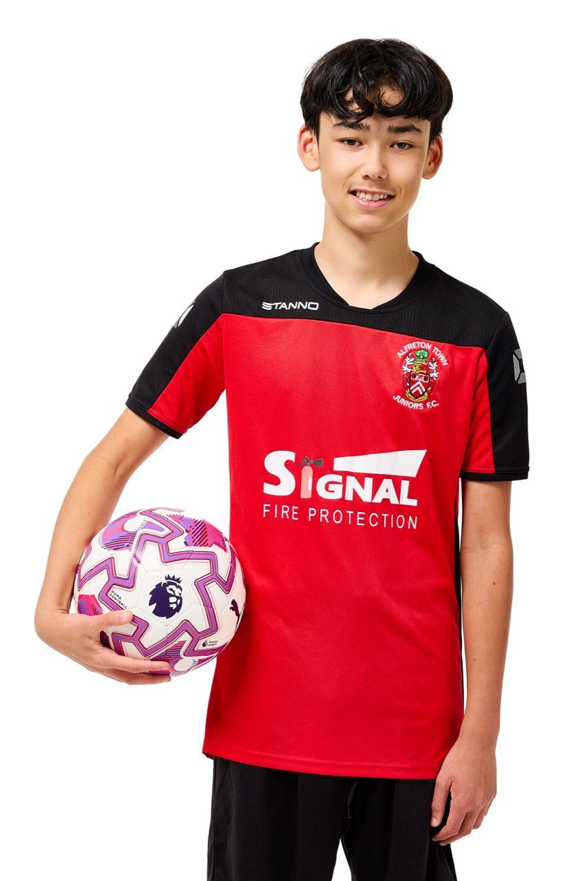 A young boy wearing a football kit and holding a ball, posing with a football against a clean white studio background.