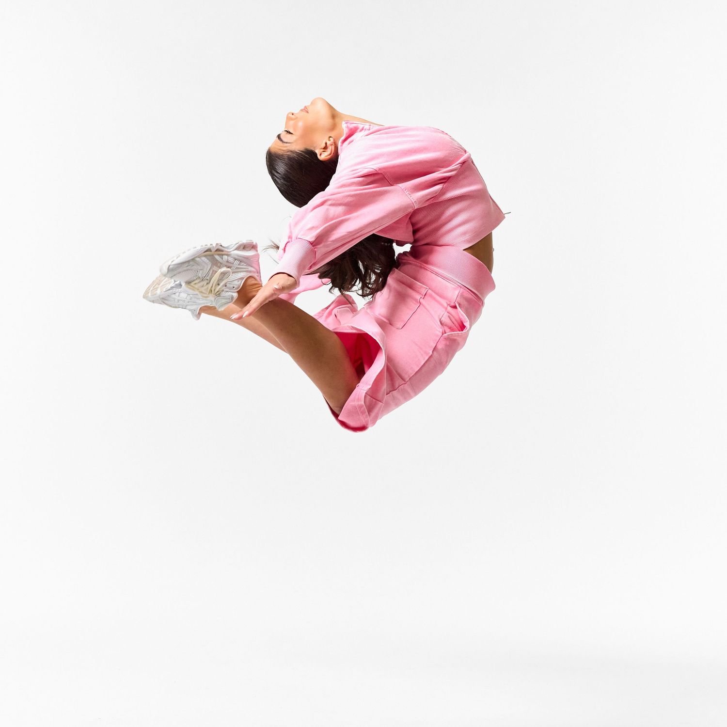 A modern dancer wearing stylish streetwear, captured in a dynamic, expressive pose against a clean white background.