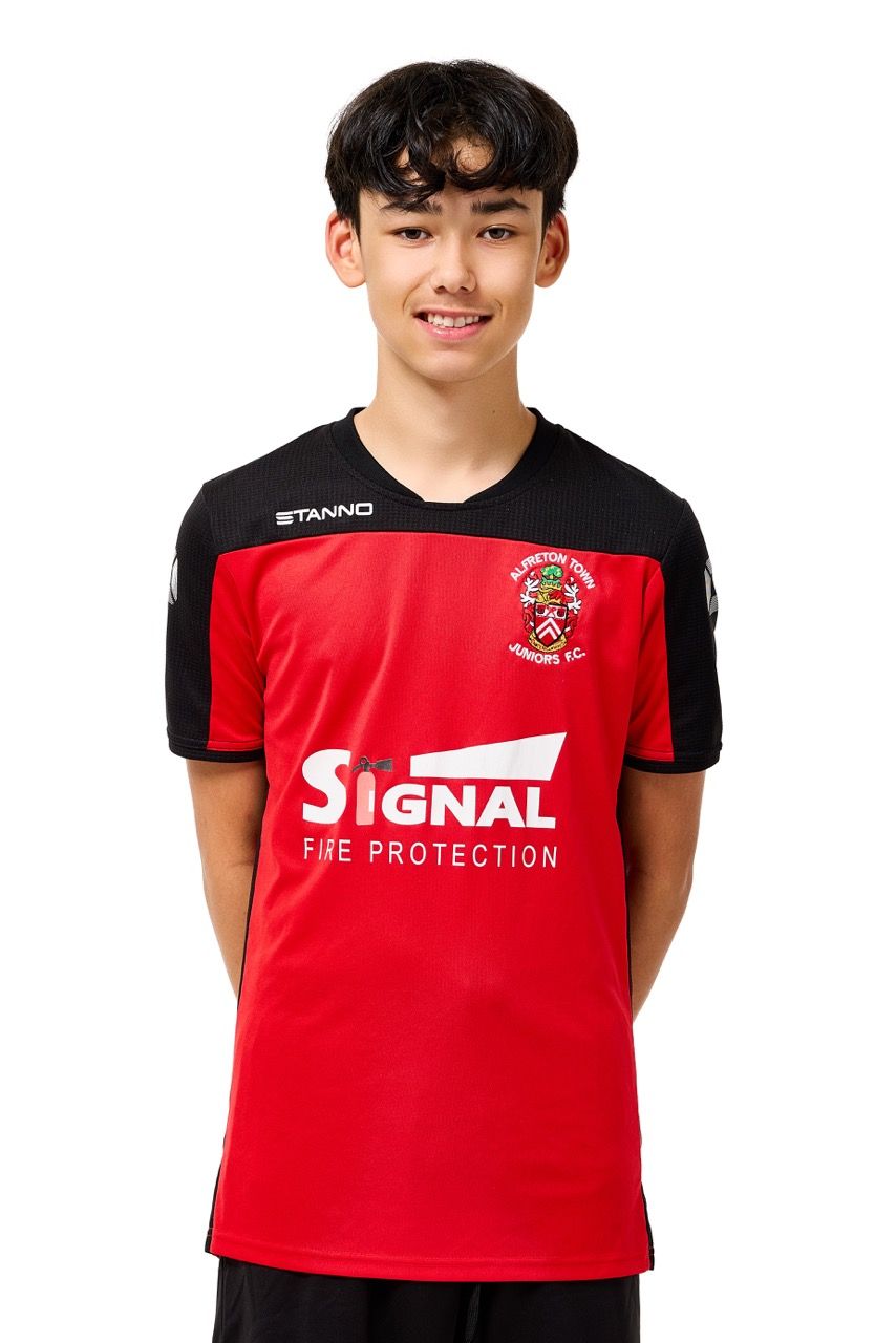 A young boy wearing a football kit, posing with a football against a clean white studio background.
