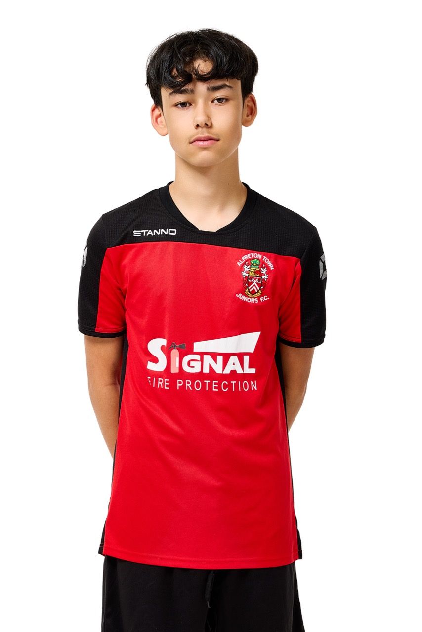 A young boy wearing a football kit, posing with a football against a clean white studio background.