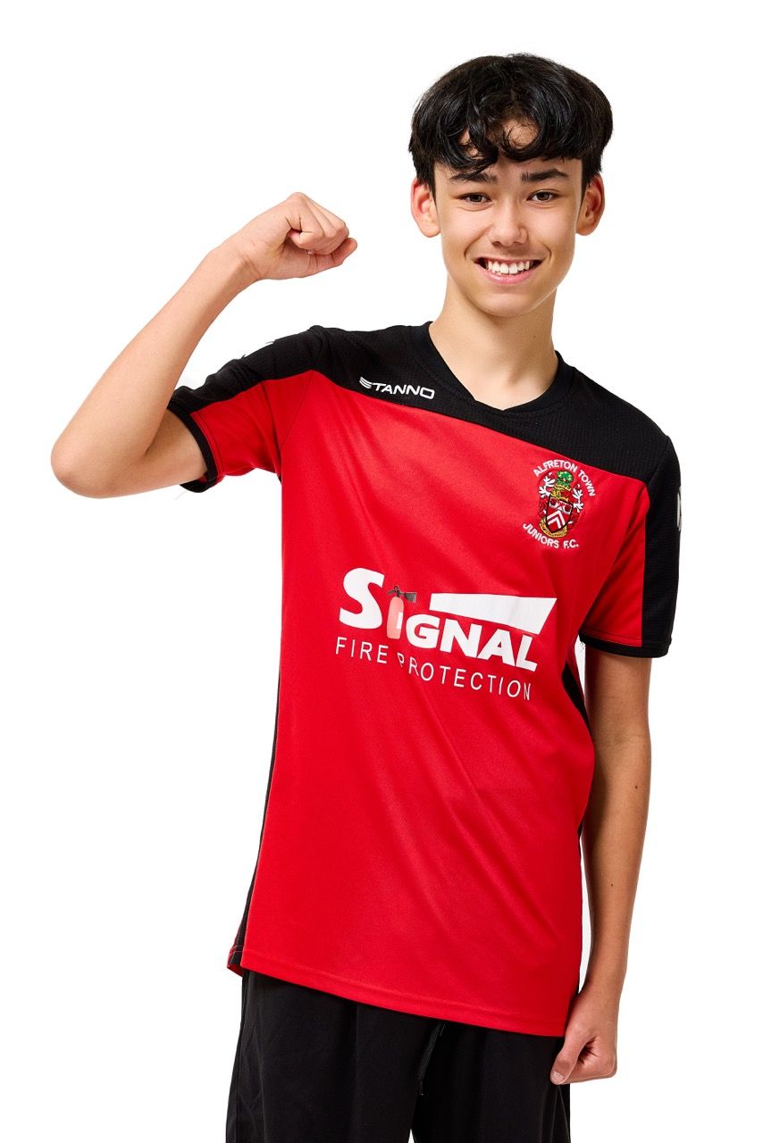 A young boy wearing a football kit, posing with a football against a clean white studio background.