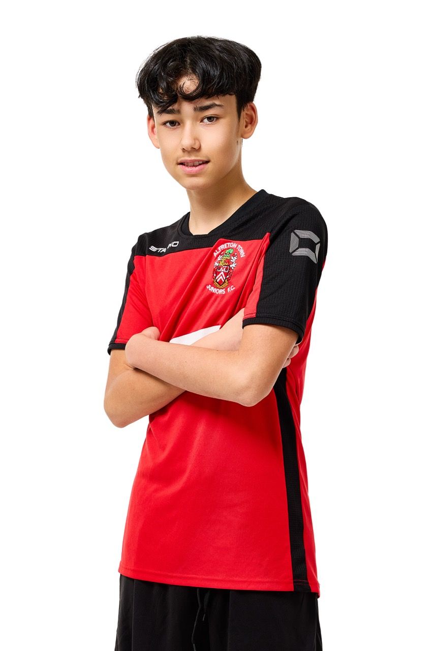 A young boy wearing a football kit, posing with a football against a clean white studio background.