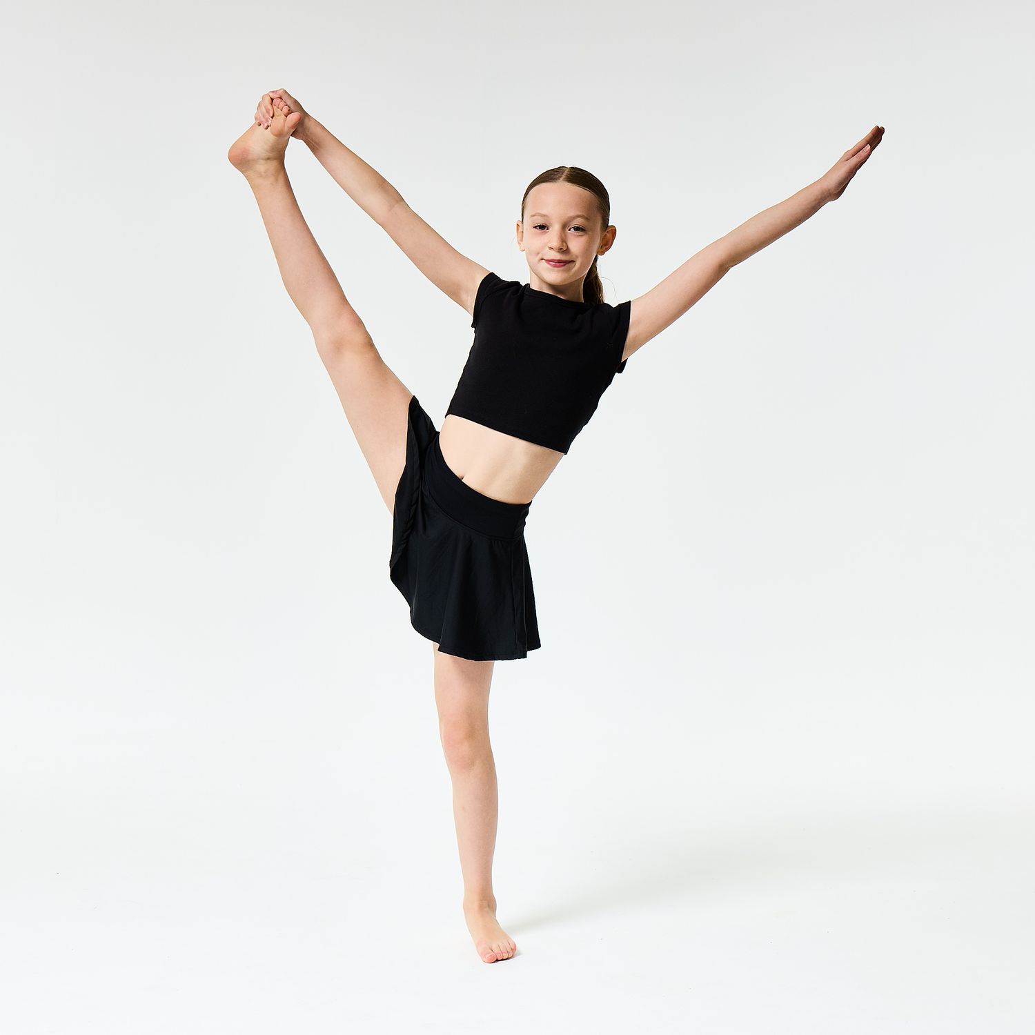 A modern dancer wearing a black vest top and shorts, captured in a sharp, athletic pose against a clean white background.