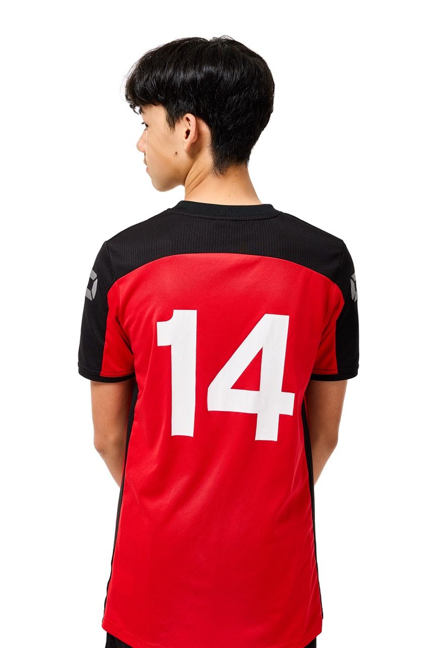 A young boy wearing a football kit, posing with a football against a clean white studio background.