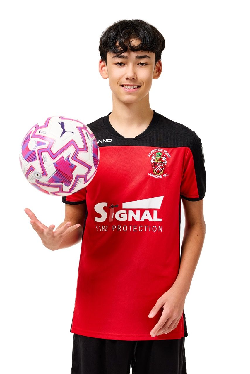 A young boy wearing a football kit and holding a ball, posing with a football against a clean white studio background.