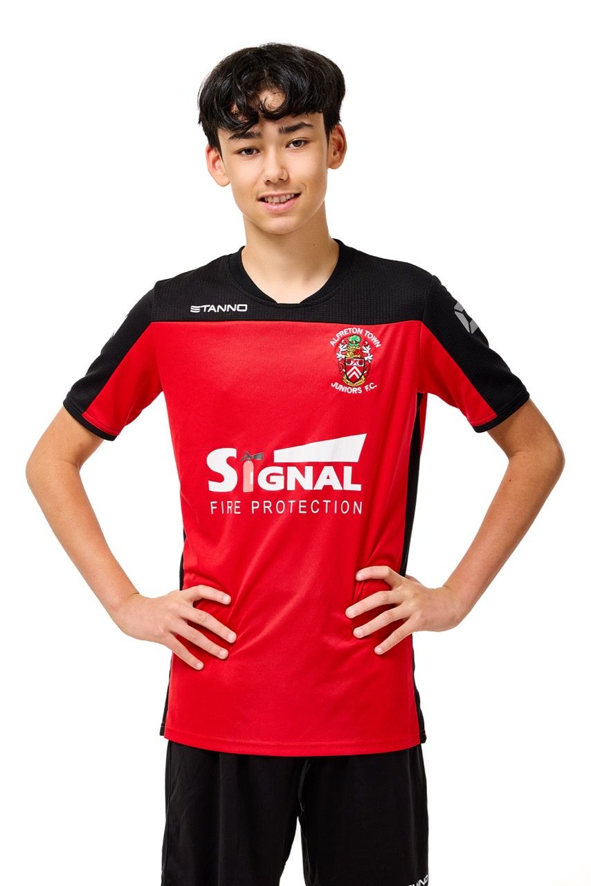 A young boy wearing a football kit, posing with a football against a clean white studio background.