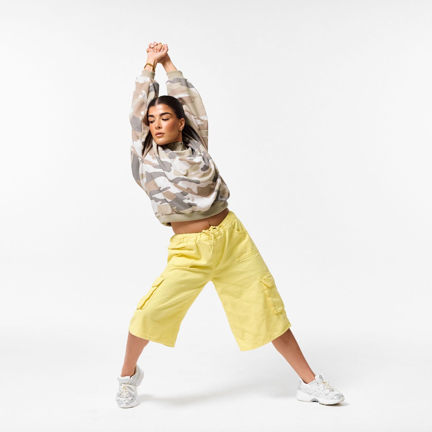 A modern dancer wearing stylish streetwear, captured in a dynamic, expressive pose against a clean white background.