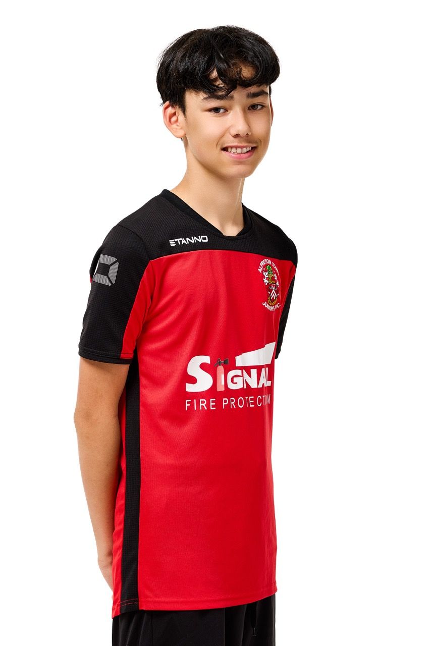 A young boy wearing a football kit, posing with a football against a clean white studio background.
