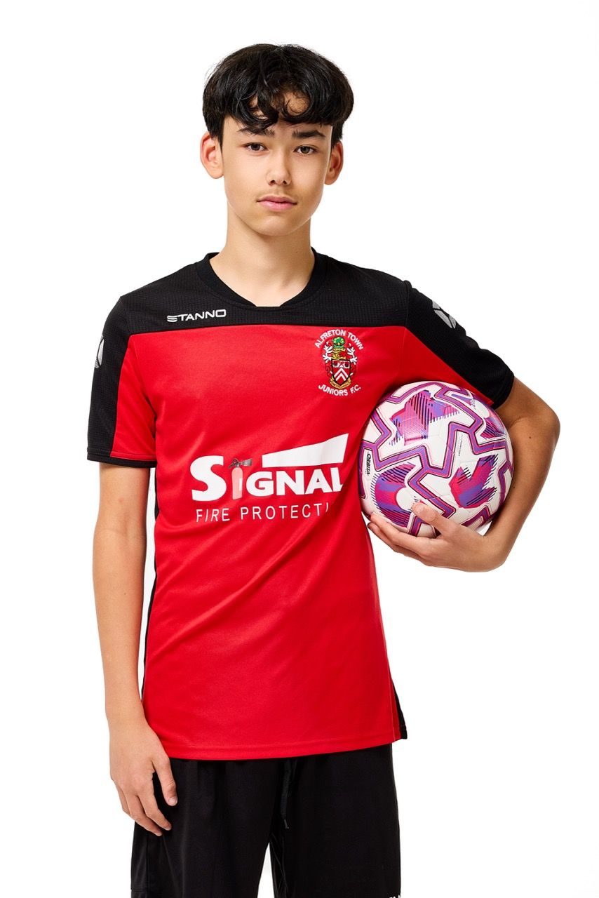 A young boy wearing a football kit and holding a ball, posing with a football against a clean white studio background.