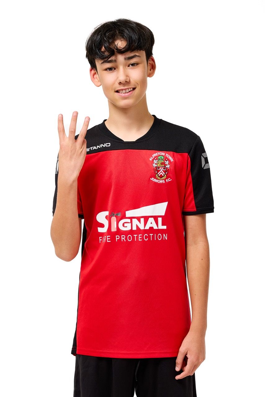 A young boy wearing a football kit, posing with a football against a clean white studio background.