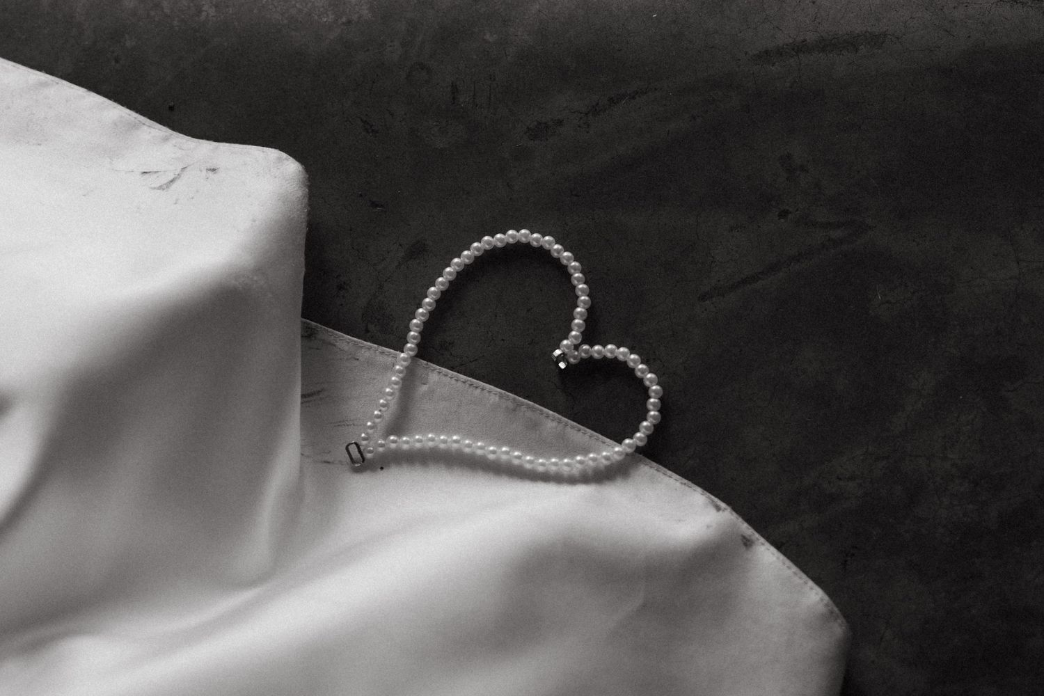 A heart shape made from wire or string casts a shadow on a smooth white surface against a dark background.