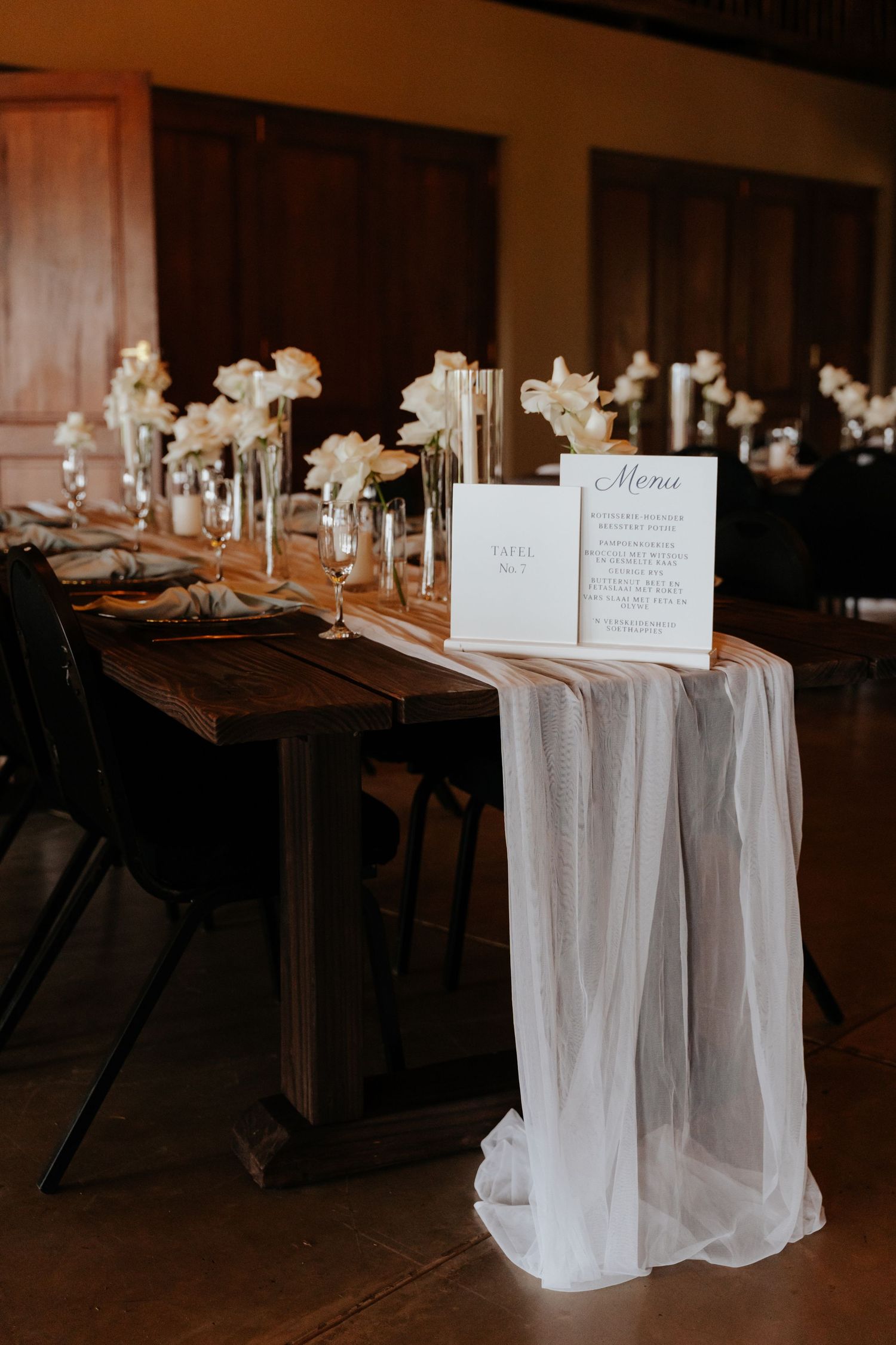 Elegant wedding reception table setup with white tulle runners and place settings.