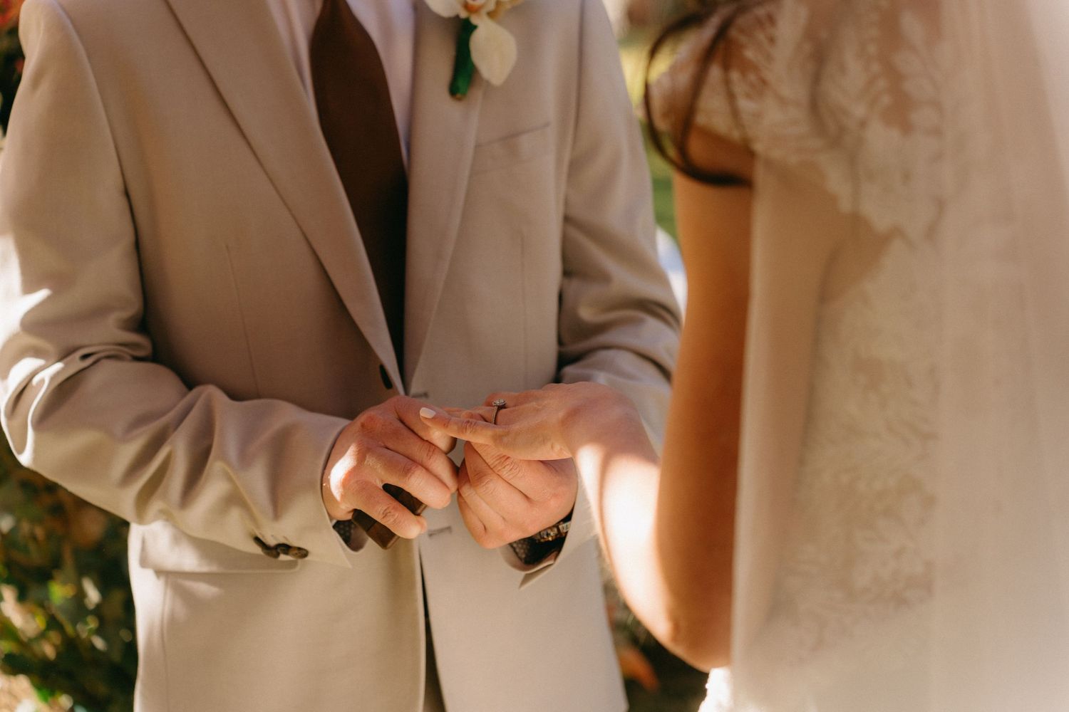 Wedding party members in light colored suits prepare for ceremony photos.