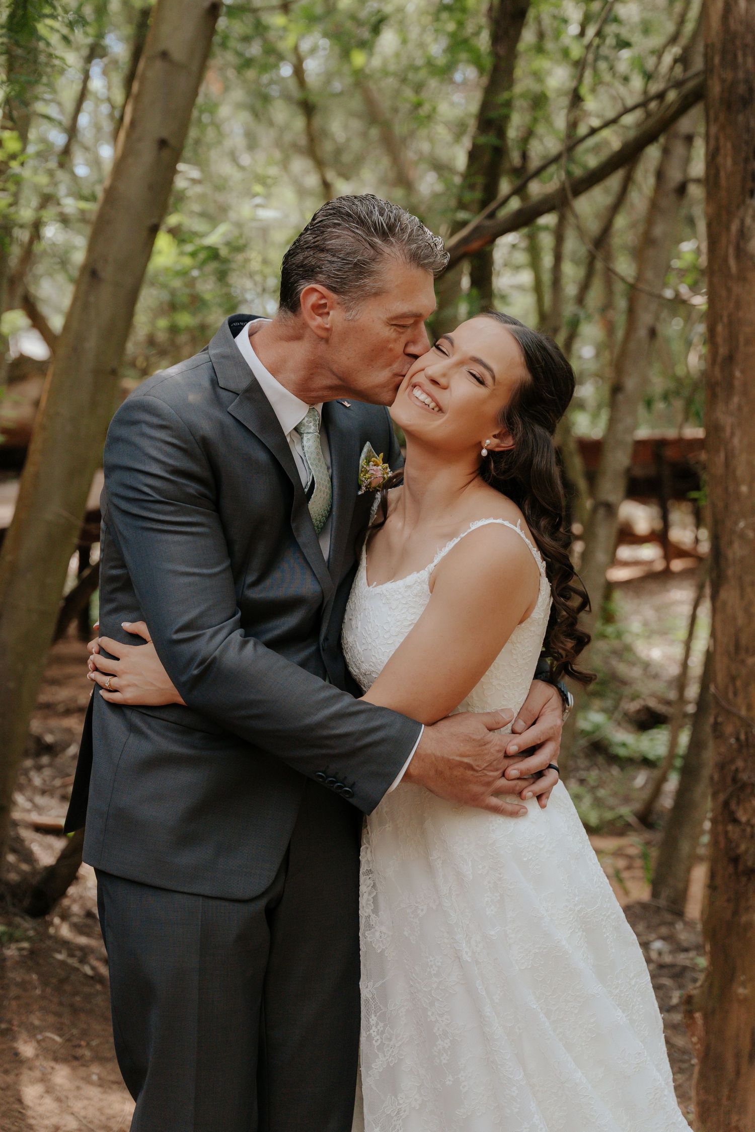 A romantic wedding couple shares intimate moments together in a wooded forest setting.