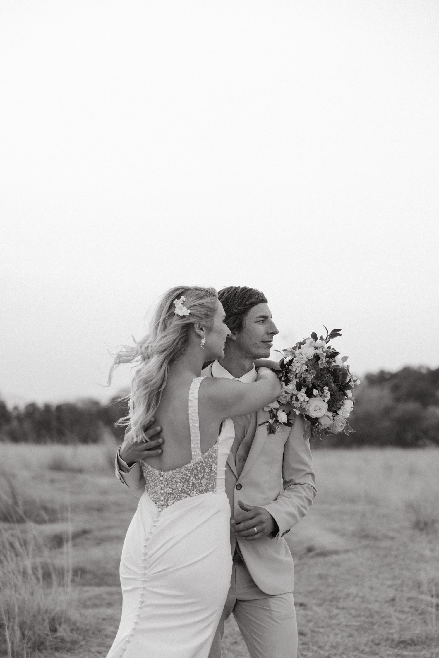 Black and white wedding photos capture intimate moments between newlyweds in a rustic outdoor setting.