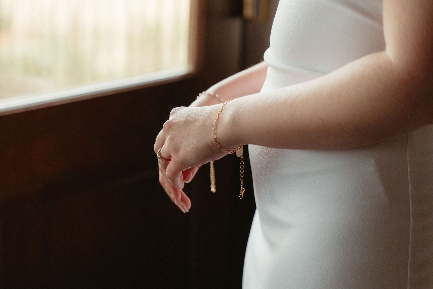Close-up view of hands adjusting white formal dress fabric in soft natural light.