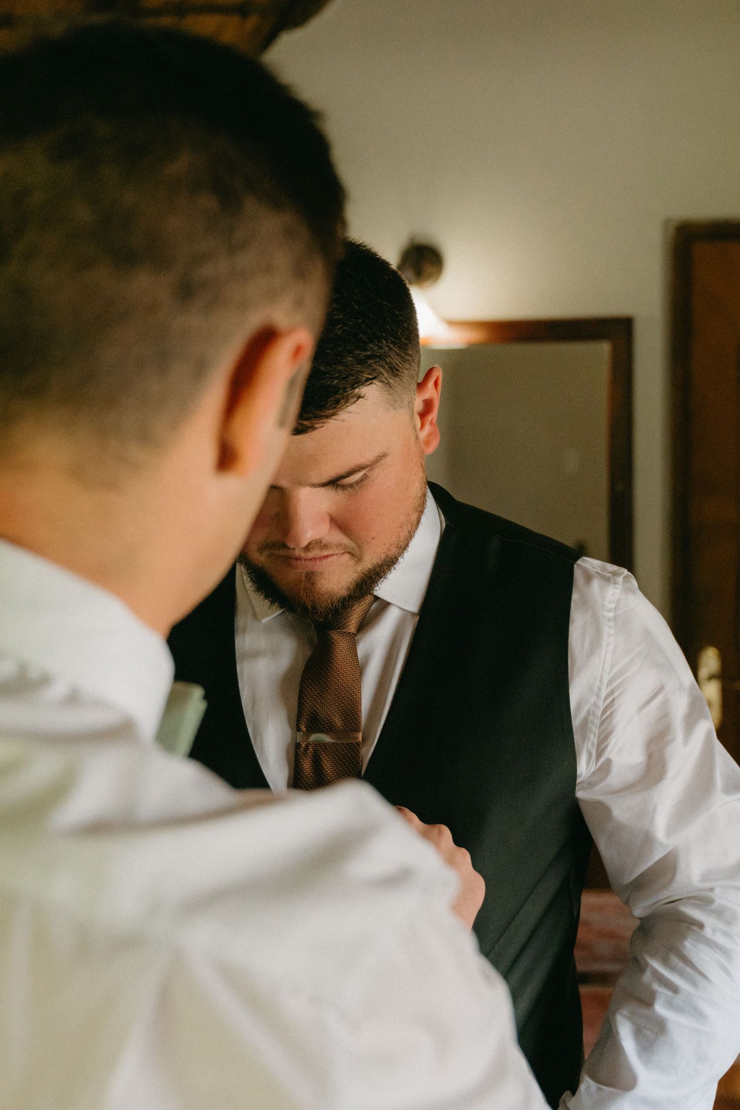 Wedding preparation moments show formal attire adjustments in dim lighting.