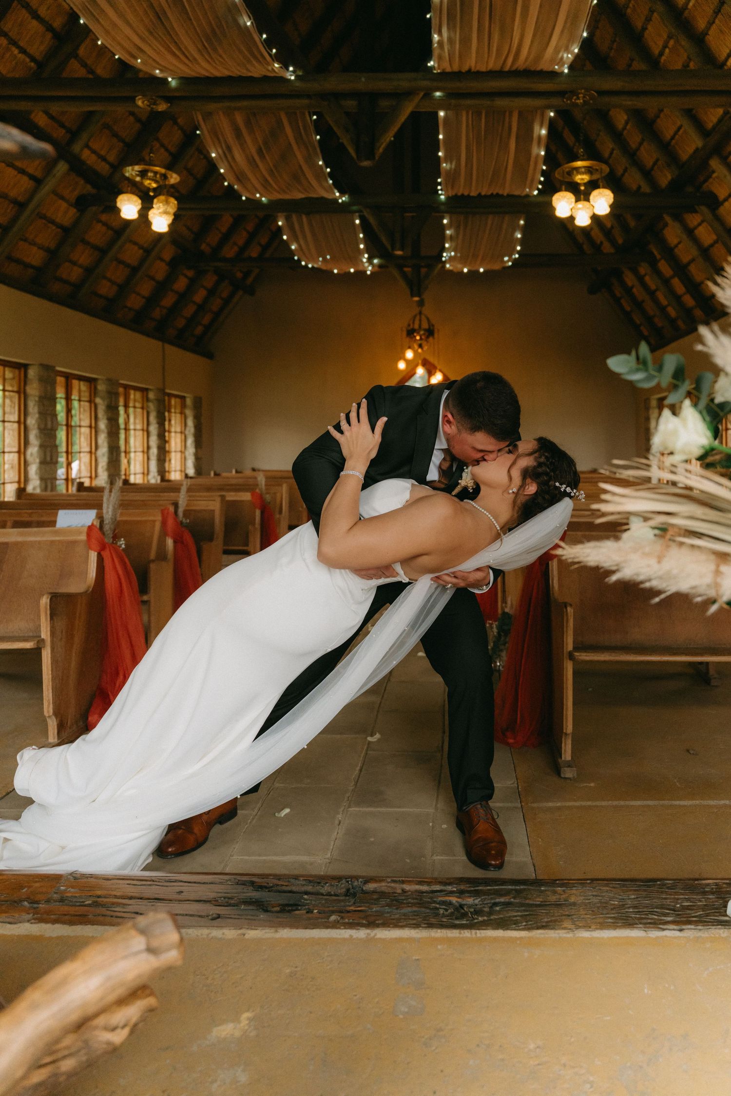 Dramatic dip dance sequence performed on a wooden floor during a wedding celebration.