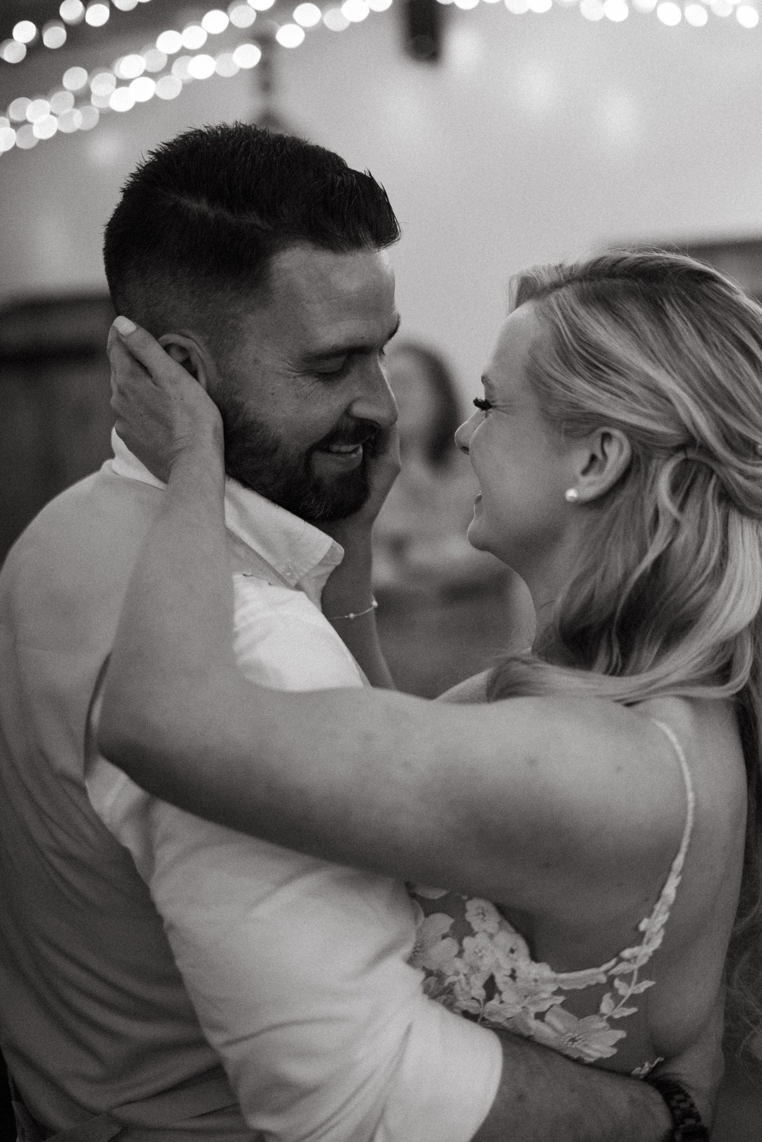 A couple shares an intimate dance moment under sparkling lights at their wedding reception.