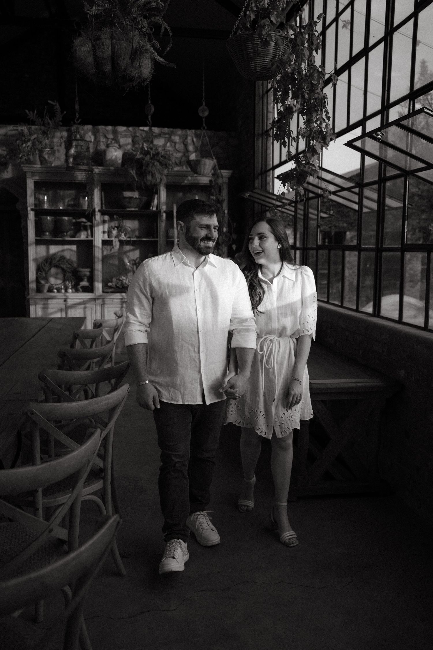 Black and white photo series showing a couple walking together in an indoor space with dramatic lighting.