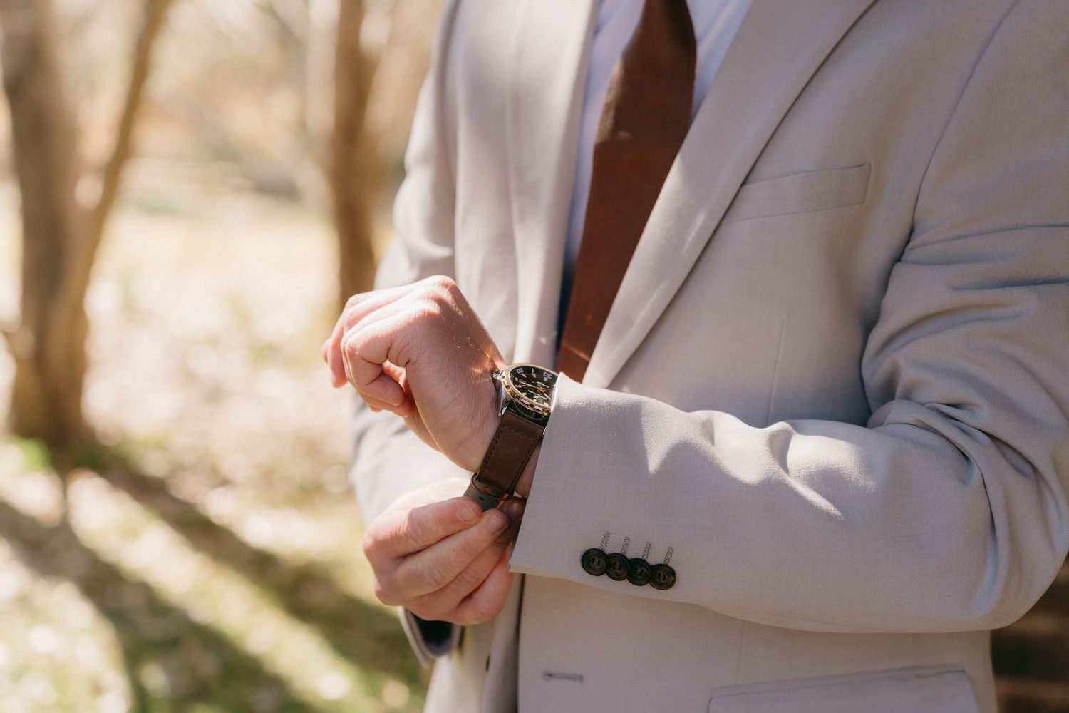Wedding party members in light colored suits pose together during formal photos.