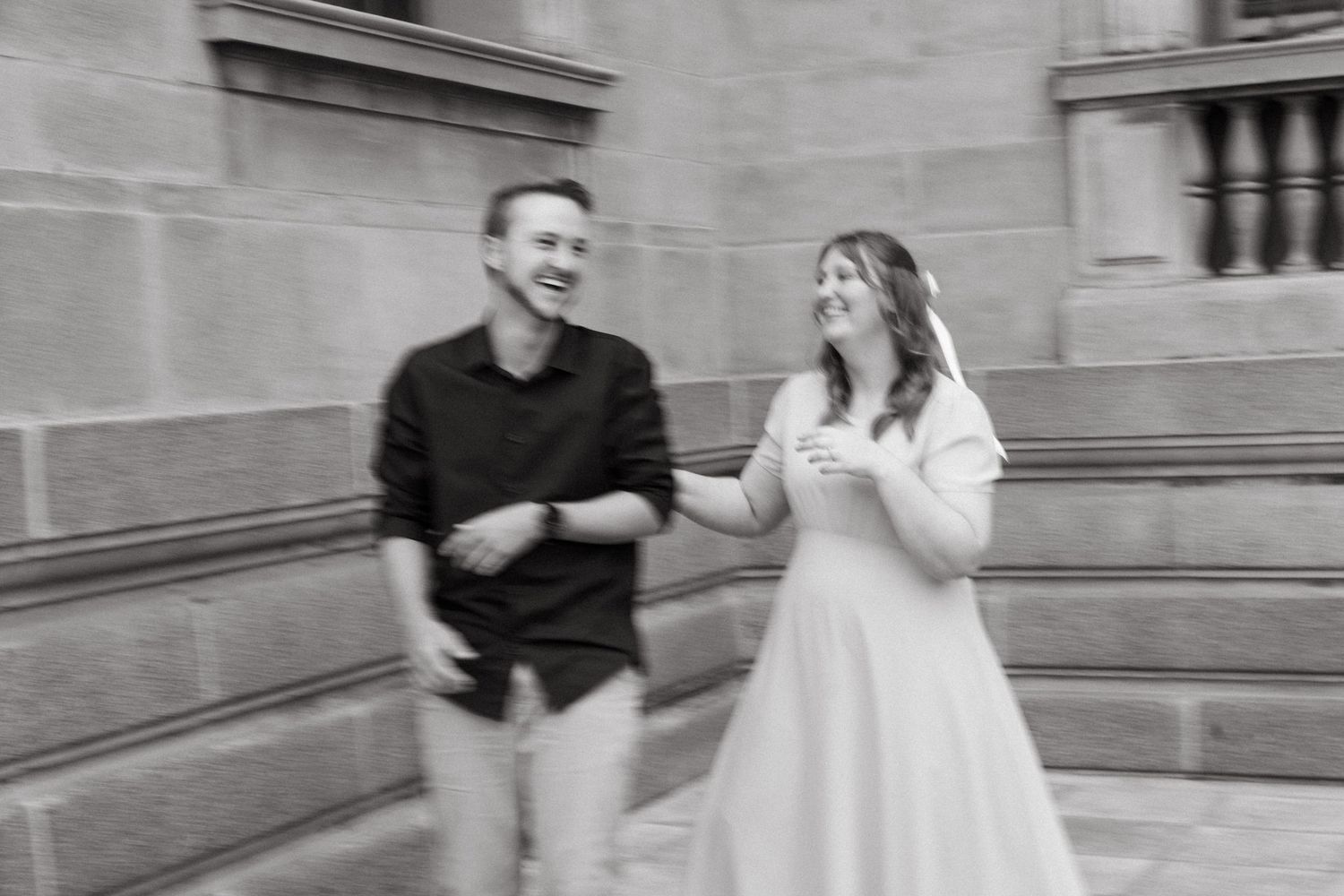 A series of black and white engagement photos showing a couple posing together outside a stone building.