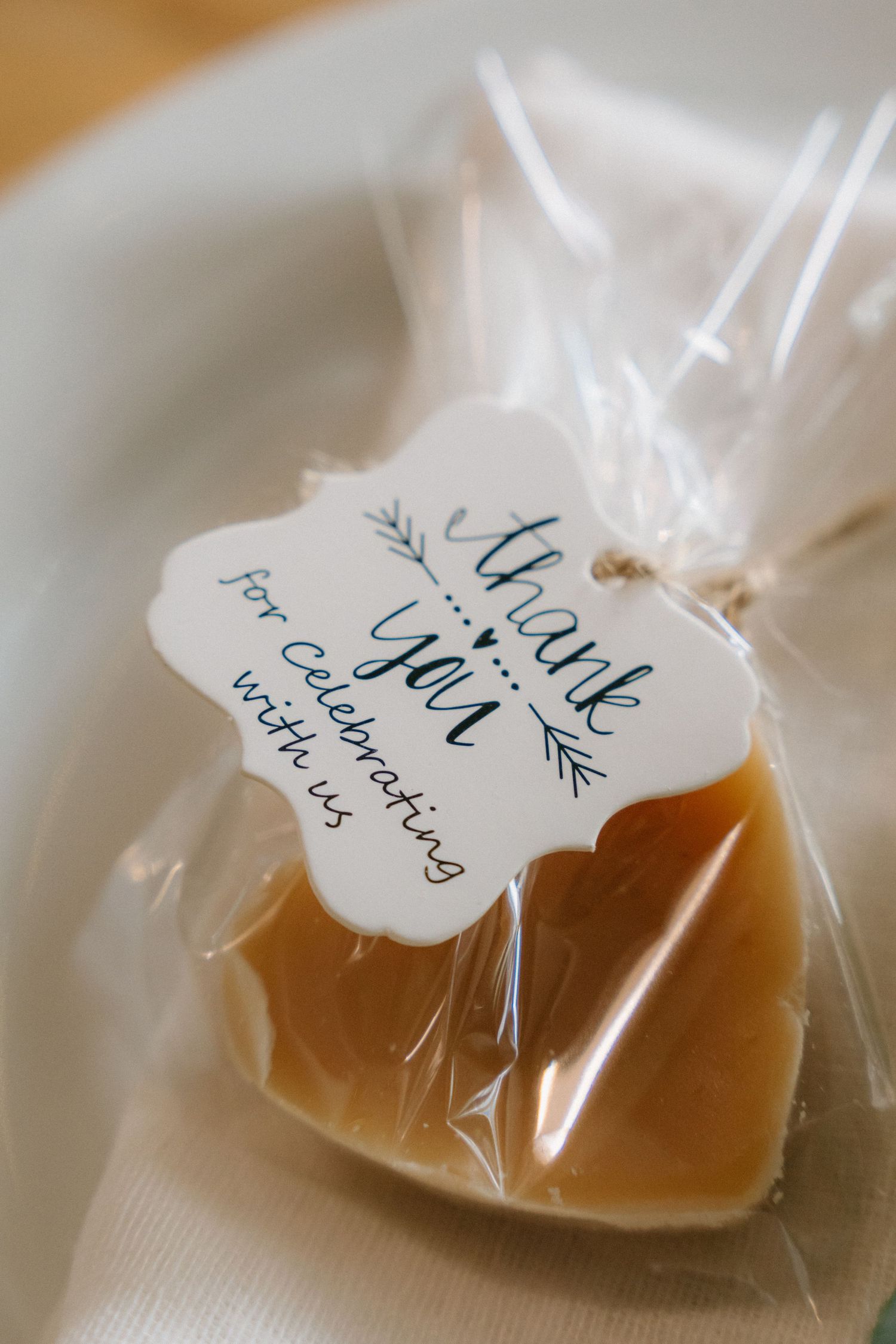Wedding favor bags with handwritten tags and caramel colored treats inside.