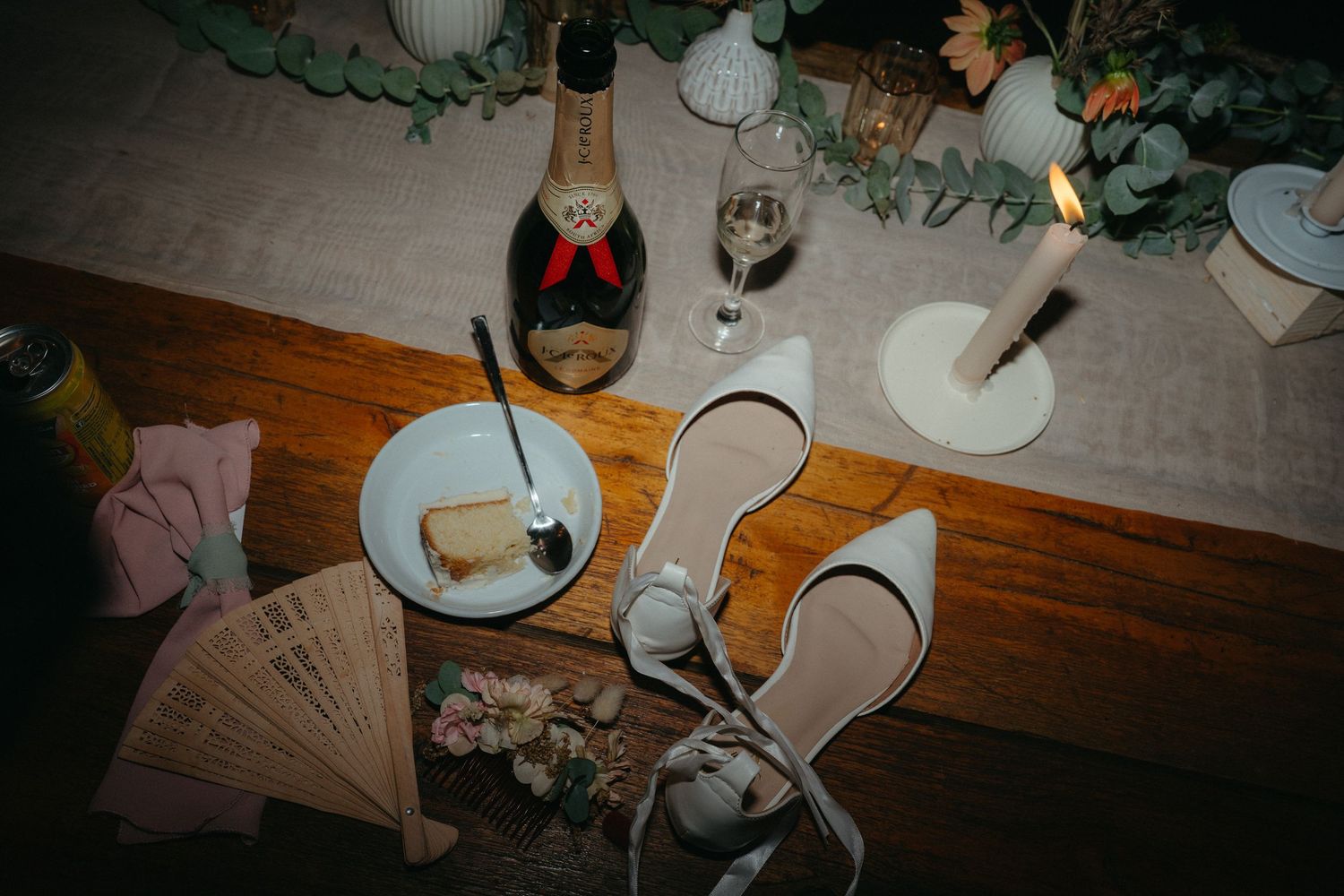 Overhead view of a wedding reception table with wine bottle, glasses, and elegant place settings on a wooden surface.