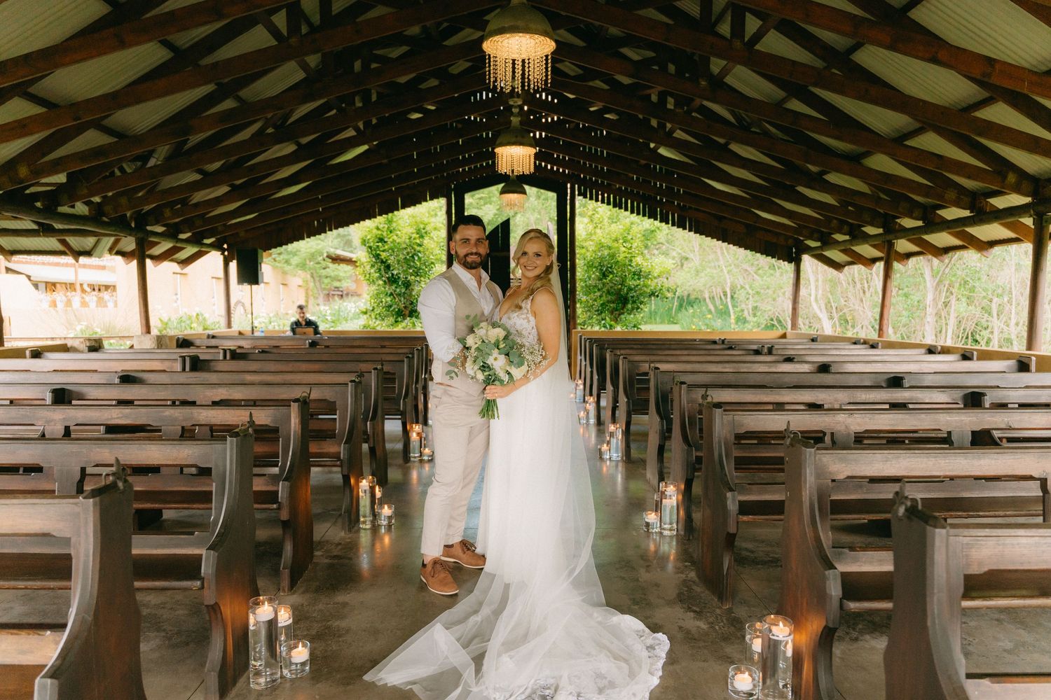 Rustic wooden barn venue decorated with string lights and white fabric for a wedding ceremony.