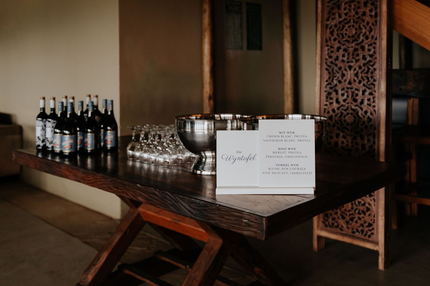 Dark moody interior setup with wine bottles and glassware on display.