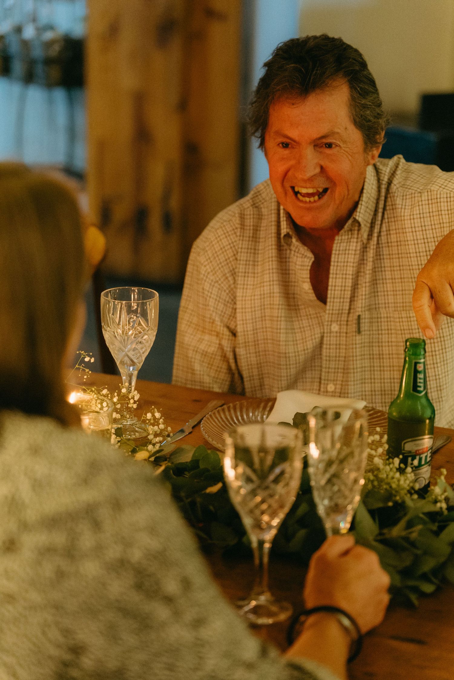 Guest enjoying dinner conversation at warmly lit wedding reception table.