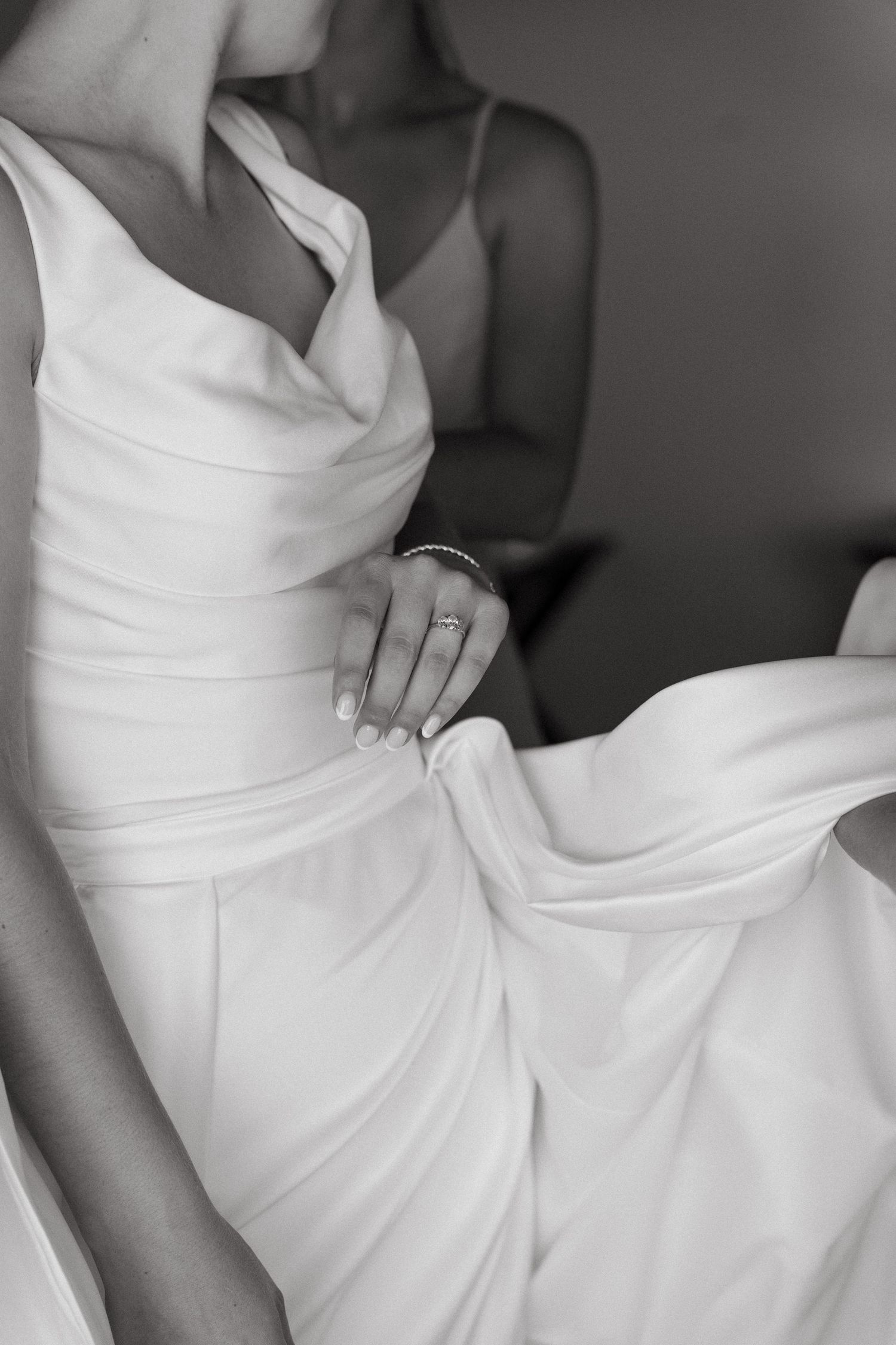 Black and white close-up details of a white wedding dress showing elegant fabric folds and textures.