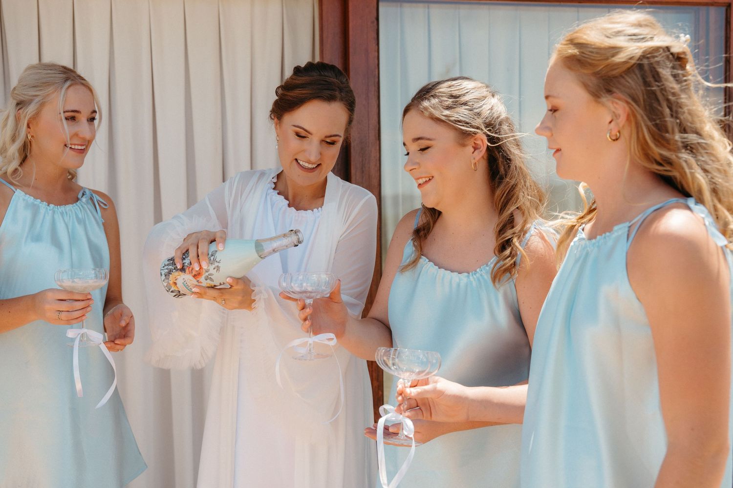A series of candid photos showing bridesmaids in light blue dresses sharing joyful moments at a wedding celebration.