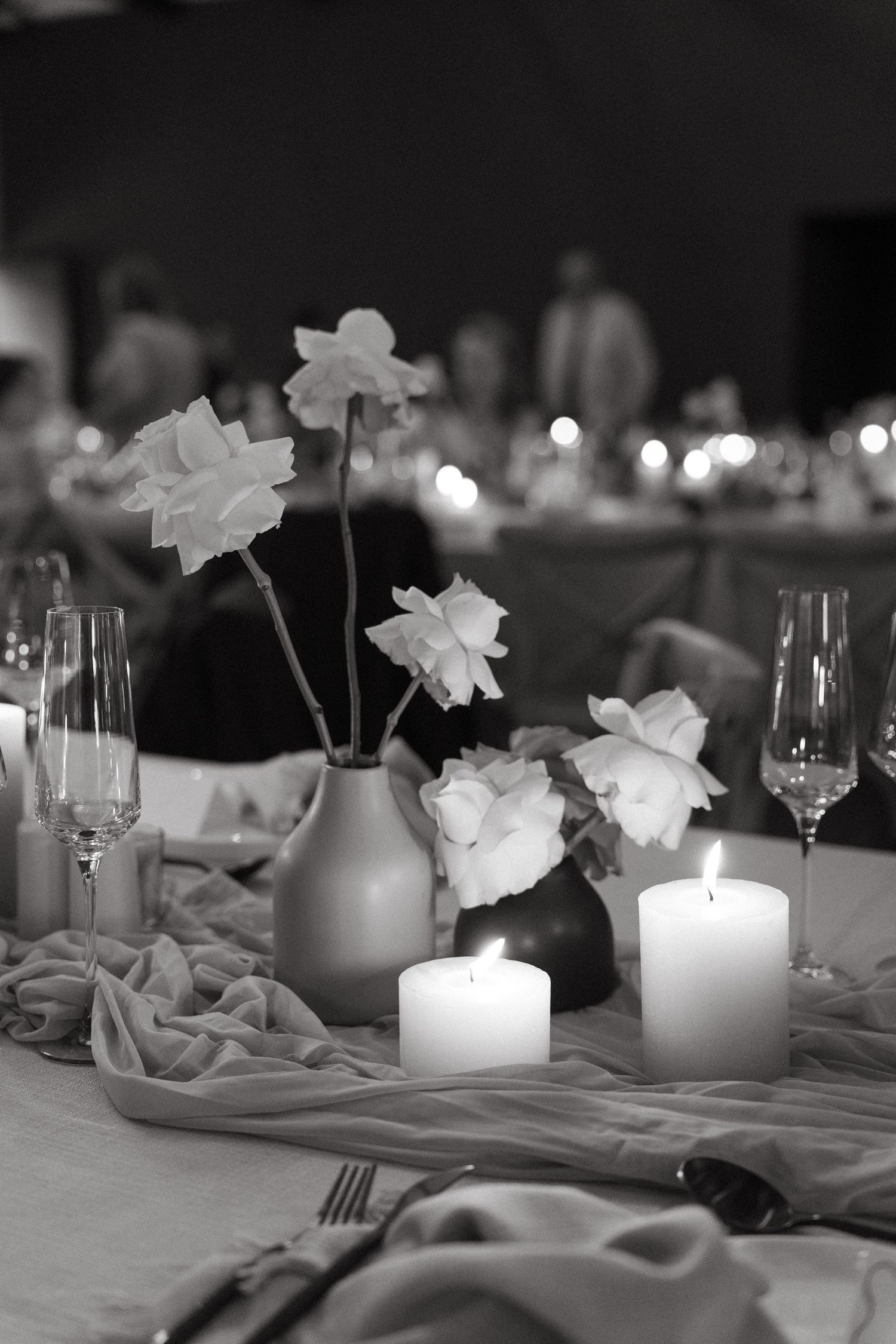 Elegant table setting with white flowers, glowing candles, and wine glasses in a dimly lit reception venue.