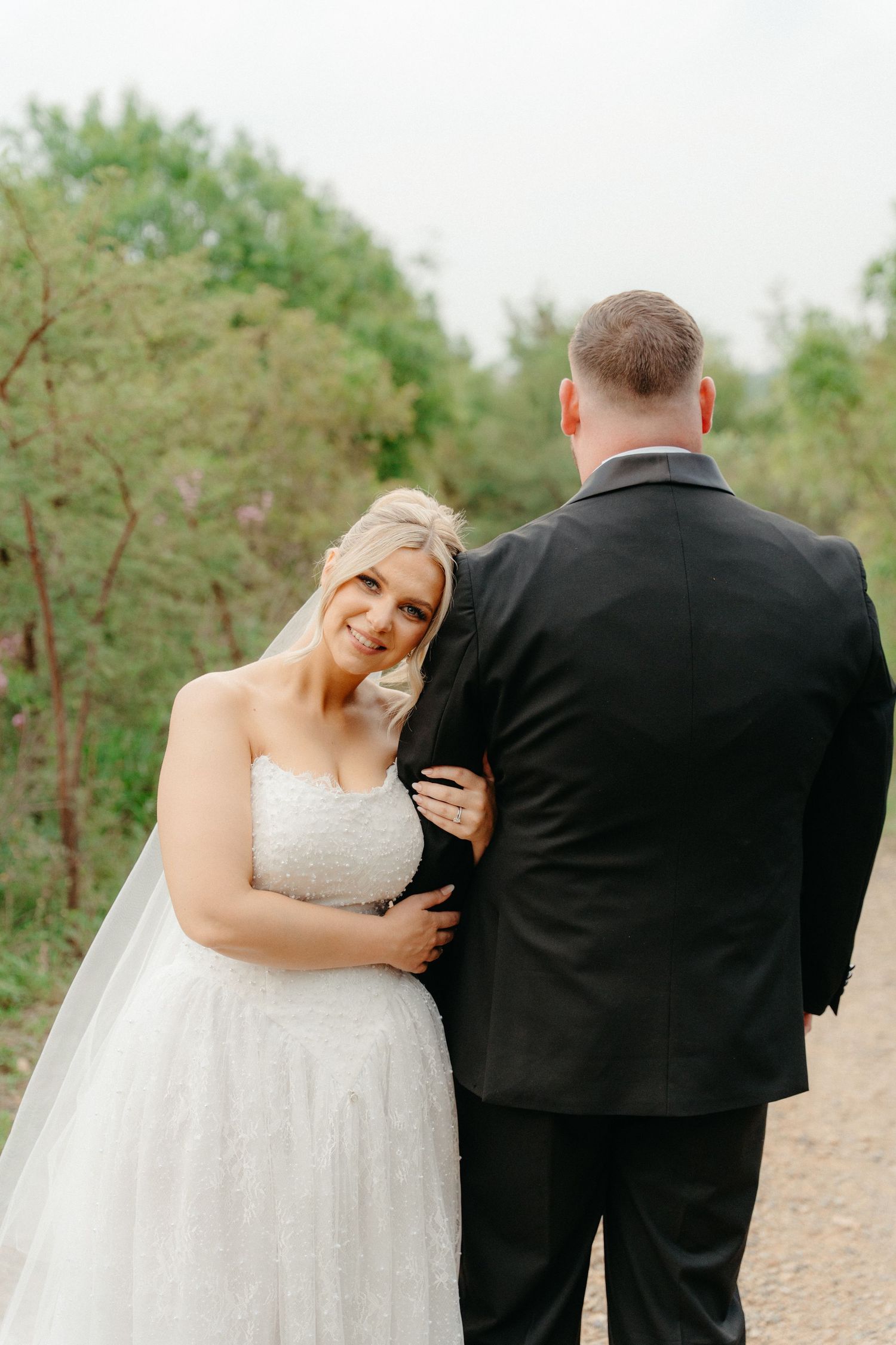 A couple shares a joyful moment together on their wedding day along a nature path.