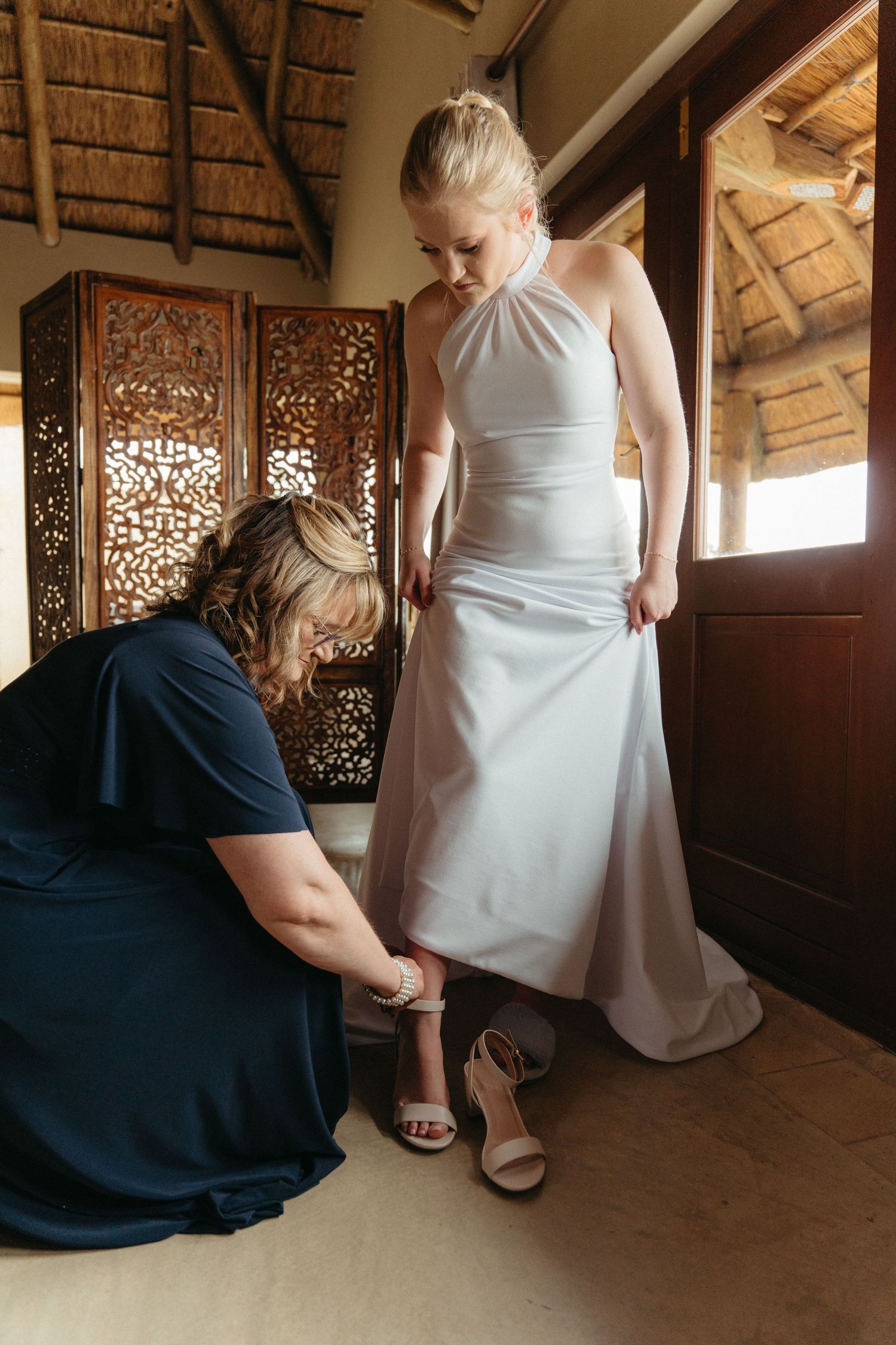 Wedding dress preparation scene with attendants helping adjust the gown.