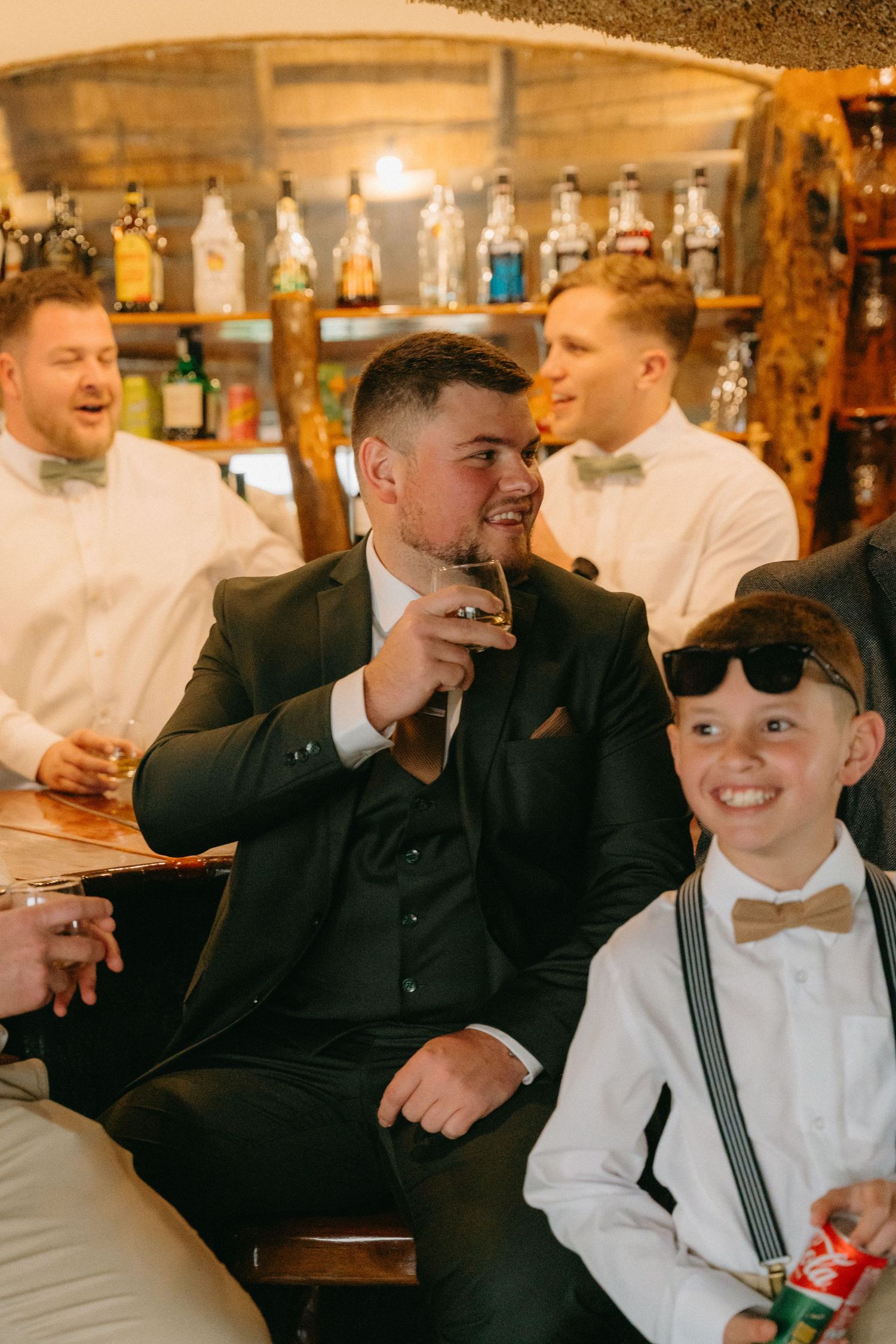 Celebratory moment at a rustic bar with formal attire and drinks.