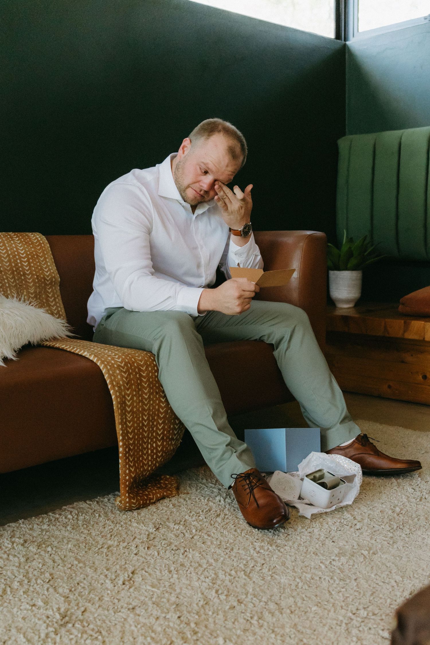 Person sitting on brown leather couch with woven accents and enjoying takeout food in modern living space.