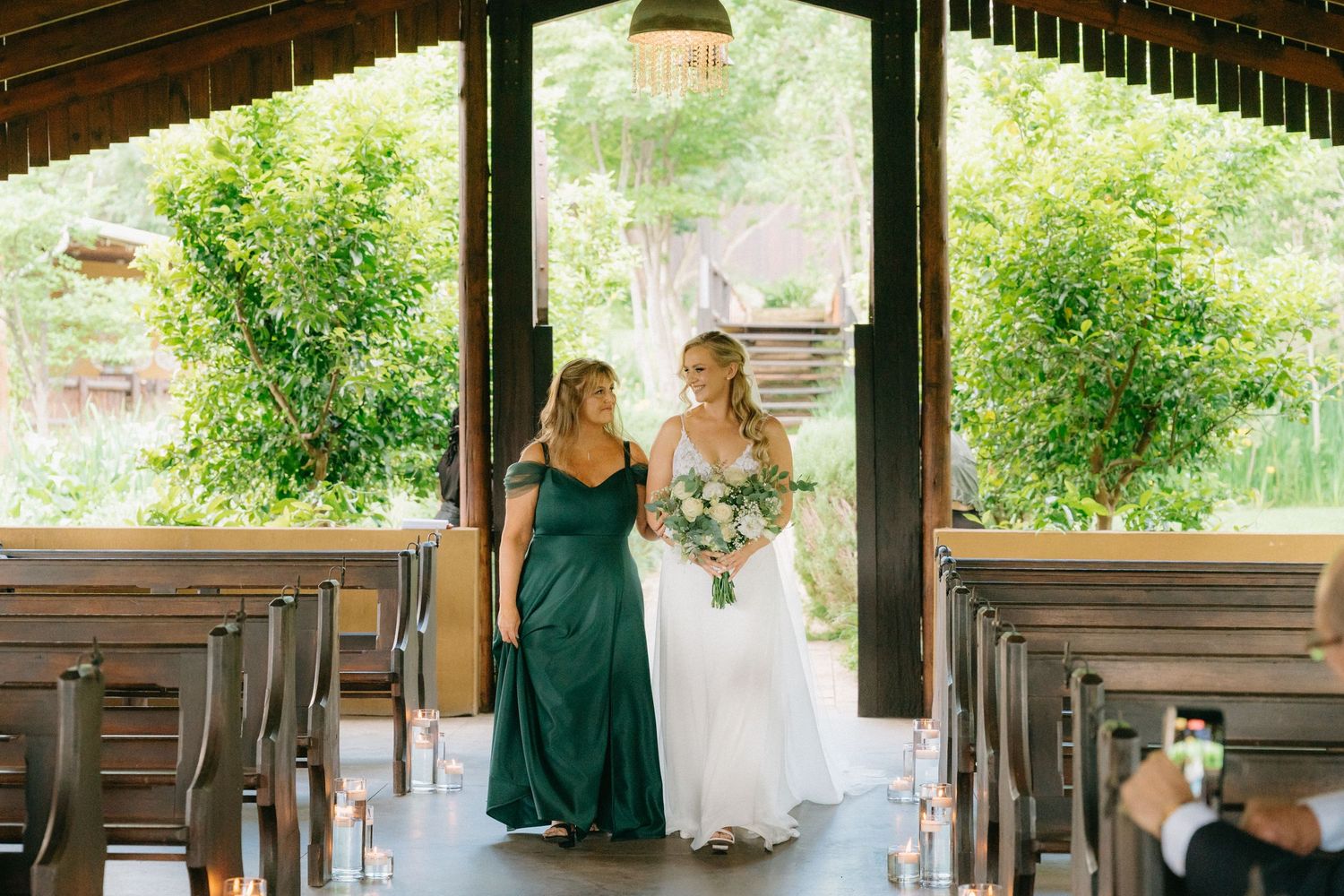 Wedding ceremony setup under rustic wooden pavilion with natural greenery.